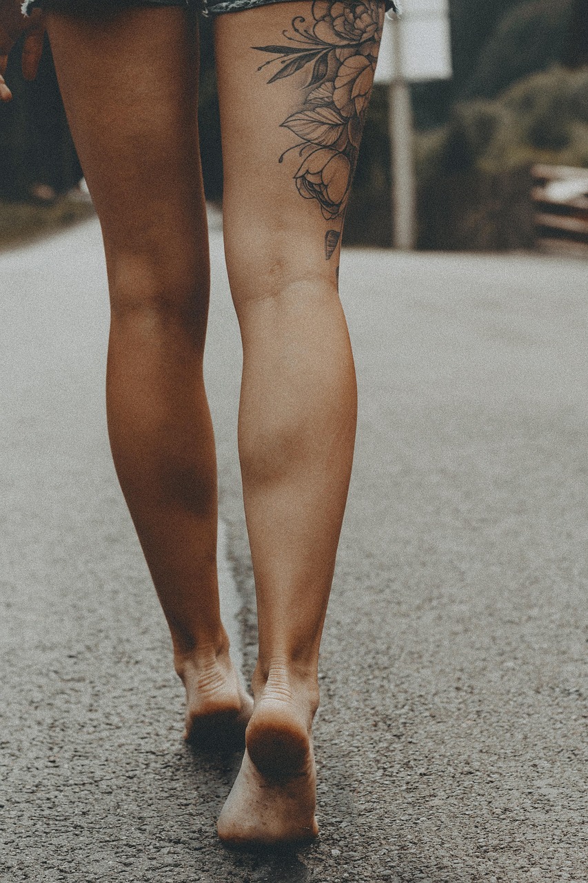 Image of a woman, just her legs, walking barefoot on a road.